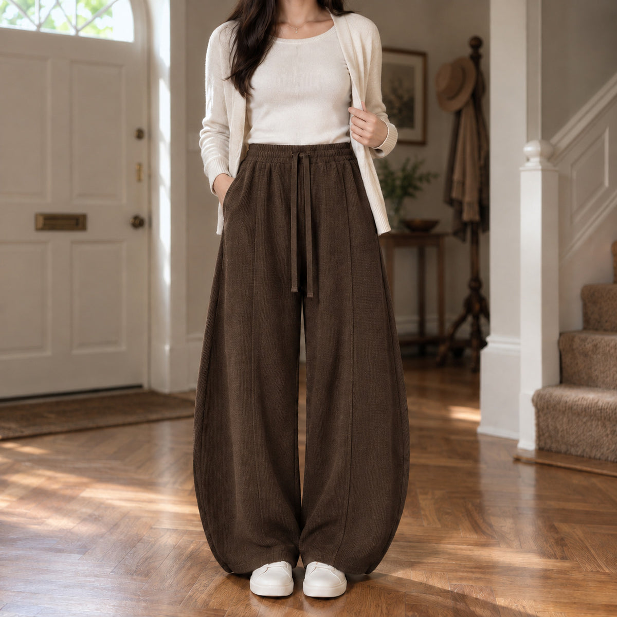 Ormsby Ribbed Wide Leg Trousers — Dark brown ribbed wide-leg pants worn by a model in a lived-in panelled room.