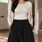 Ormsby Ribbed Wide Leg Trousers — Black ribbed wide-leg pants worn, cropped from the shoulders to the waist to show the elastic waistband and ribbed knit.