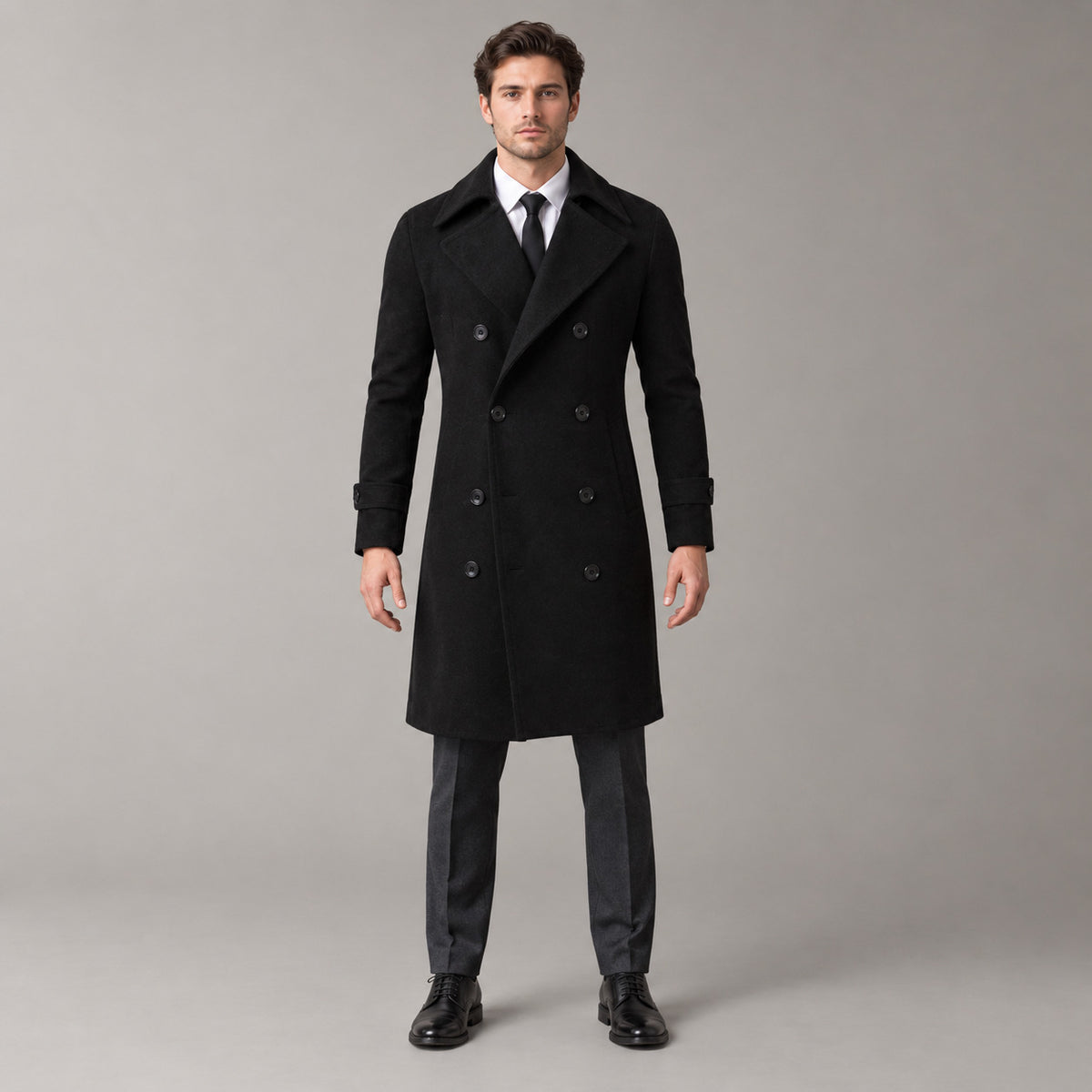 Norbury Cotton Blend Trench Coat — Black double-breasted trench coat worn by a model against a pale stone studio backdrop.