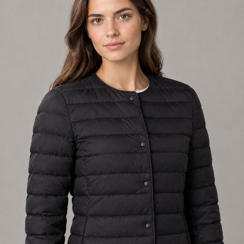 Hatherley Quilted Down Jacket — Black collarless quilted down jacket worn, cropped from the shoulders to the waist to show the round neckline and snap front closure.